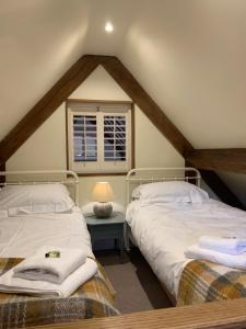 2 Betten in einem Schlafzimmer im Dachgeschoss mit Fenster in der Unterkunft Stable Cottage in Dorking