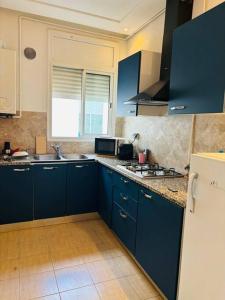 a kitchen with blue cabinets and a white refrigerator at Appartement Marsa Ville in La Marsa