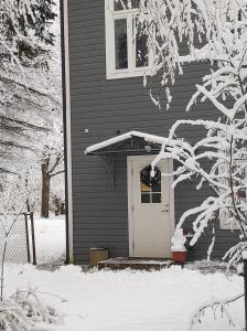 una casa con una puerta blanca en la nieve en Elva Stuudiomajutus en Elva