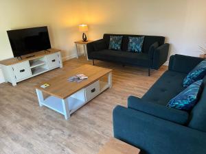 a living room with two couches and a television at Cosy Hillside Annex in Stanwick +15 photos