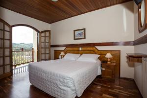 1 dormitorio con 1 cama grande y balcón en Hotel Leão da Montanha, en Campos do Jordão