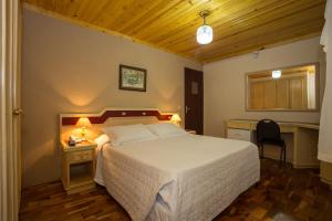 a bedroom with a bed and a desk and a chair at Hotel Leão da Montanha in Campos do Jordão