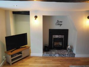 a living room with a tv and a fireplace at Stone Cottage in Morpeth