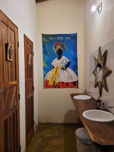 a bathroom with a painting of a woman holding bananas at Family Guest House in Ilha de Boipeba