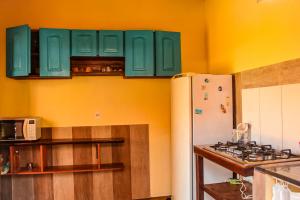 a kitchen with green cabinets and a white refrigerator at Family Guest House in Ilha de Boipeba