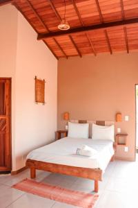 a bedroom with a white bed with a wooden ceiling at Family Guest House in Ilha de Boipeba