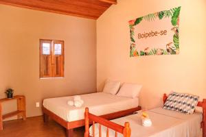 a room with two beds and a table and a window at Family Guest House in Ilha de Boipeba