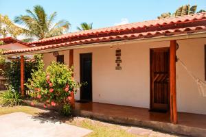 a small white house with a door and a bush at Family Guest House in Ilha de Boipeba
