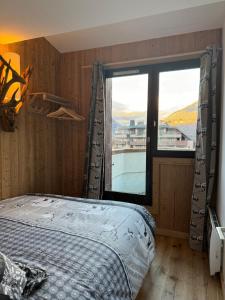 een slaapkamer met een bed en een groot raam bij Cocon au cœur de Chamonix avec parking gratuit in Chamonix-Mont-Blanc