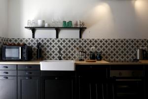a kitchen with a sink and a black and white tile wall at Maison - Les Traversières in Eymet