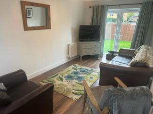 a living room with a couch and a tv at Immaculate house in Doncaster in Cantley