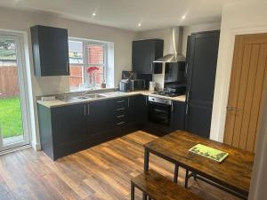 a kitchen with black cabinets and a wooden table at Immaculate house in Doncaster in Cantley