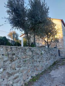 un mur en pierre avec deux arbres et un bâtiment dans l'établissement Casa das Cortes - Serra da Estrela, à Gouveia