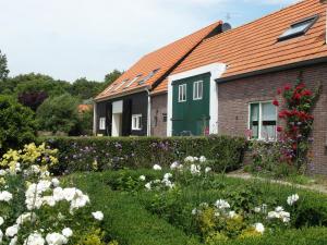 a house with a green door and a garden with flowers at het Neerland in Biggekerke