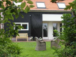 une maison noire avec un banc dans la cour dans l'établissement het Neerland, à Biggekerke