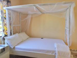 1 cama con dosel blanco en una habitación en Stay with Adventures of Marie, en Watamu