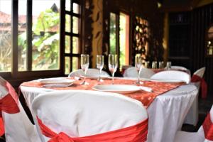 una mesa con sillas blancas y copas de vino. en Hosteria Hachacaspi, en Puyo