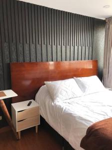 een bed met een houten hoofdeinde en een nachtkastje bij Apto confortable zona estratégica al Aeropuerto in Bogota