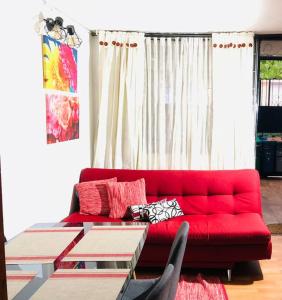 een rode bank in een woonkamer met een tafel bij Apto confortable zona estratégica al Aeropuerto in Bogota