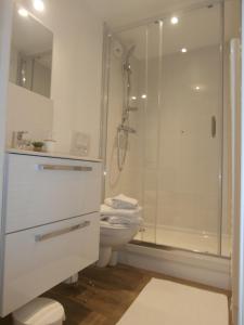 a white bathroom with a shower and a toilet at au Claire de lune in Dieppe