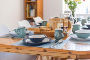 a wooden table with plates and cups and utensils on it at Shalom - holiday home with panoramic views of the sea in Kingsdown