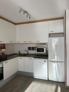 a kitchen with white cabinets and a stainless steel refrigerator at Apartment Foix in Cubelles