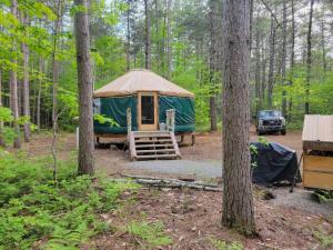 a green tent in the woods with a jeep parked at Rufus III Yurt on the river in Brownfield