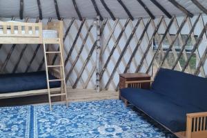 a room with a bunk bed and a couch in a yurt at Allie Mae Yurt nestled in the woods in Brownfield