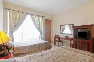 a bedroom with two beds and a desk and a television at Puri Sawo Manila Residence in Jakarta