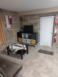 ein Wohnzimmer mit einem TV und einer Tür in der Unterkunft Casa das Cortes - Serra da Estrela in Gouveia