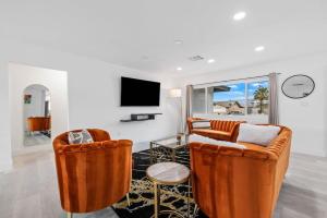 a living room with two orange chairs and a tv at NEW Sip Sip Away A Vibrant Pool and Hot Tub Retreat in Palm Springs