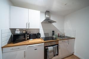 a kitchen with white cabinets and a microwave at Cozy 2-Bedroom Ground-Floor Apt near Kirkstall Shopping Centre in Leeds