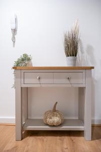 a console table with a wooden top and a pumpkin on a shelf at Cozy 2-Bedroom Ground-Floor Apt near Kirkstall Shopping Centre in Leeds