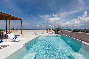 Una piscina con sillas y el océano al fondo. en Bondo Estudio, en Cartagena de Indias