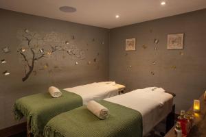 two beds in a room with a tree on the wall at Montcalm Chilworth Townhouse, Paddington in London