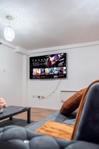 a living room with a couch and a tv on the wall at Spacious 2 Bedroom 6 Minute Drive from Huddersfield Town Centre - Ideal Stay in Huddersfield
