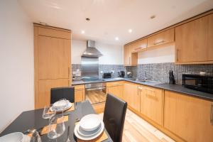 a kitchen with wooden cabinets and a table with chairs at Spacious 2 Bedroom 6 Minute Drive from Huddersfield Town Centre - Ideal Stay in Huddersfield