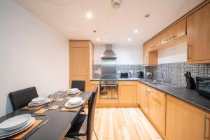 een keuken met een tafel met stoelen en een aanrecht bij Spacious 2 Bedroom 6 Minute Drive from Huddersfield Town Centre - Ideal Stay in Huddersfield