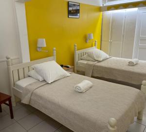 two beds in a room with yellow walls at Hotel Le Rotabas in Sainte-Anne