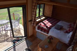 a small bedroom with a bed and a balcony at The Flying Scotsman Shepherd's Hut with Hot Tub in Brecon