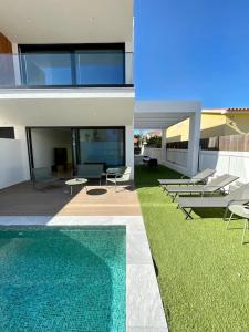 a house with a swimming pool and some chairs at SereneScape Villa - Fernão Ferro in Fernao Ferro