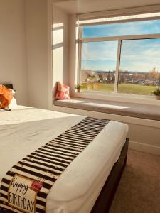 a bedroom with a bed with a happy birthday pillow and a window at Sweet home (mountain view) in Surrey