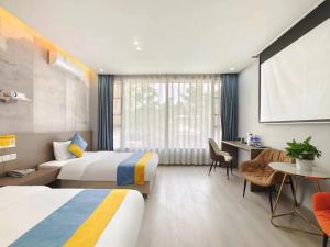 a hotel room with two beds and a desk at Xian Feng Hotel - Tianfu International Airport Branch in Jianyang