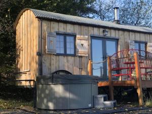 a tiny house with a trash can in front of it at The Orient Express Shepherd's Hut with Hot Tub in Brecon