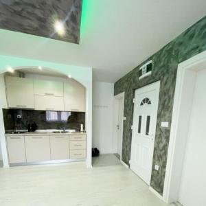 a kitchen with white cabinets and a green wall at Apartman Tijana in Pale