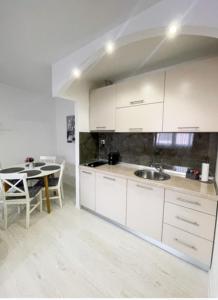 a kitchen with white cabinets and a dining table at Apartman Tijana in Pale