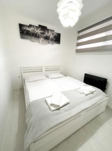 Habitación blanca con 2 camas y lámpara de araña. en Apartman Tijana, en Pale