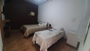 1 dormitorio con 2 camas y mesa. en Rancho Esperança, pouso e comida a lenha, en Paraty