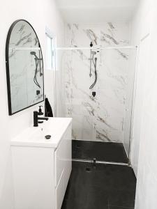 uma casa de banho branca com um chuveiro e um lavatório. em Stunning Queen Room 1Min Walk to Station with 55 Inch TV em Sydney