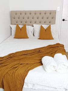 a large bed with orange and white pillows at Stunning Queen Room 1Min Walk to Station with 55 Inch TV in Sydney
